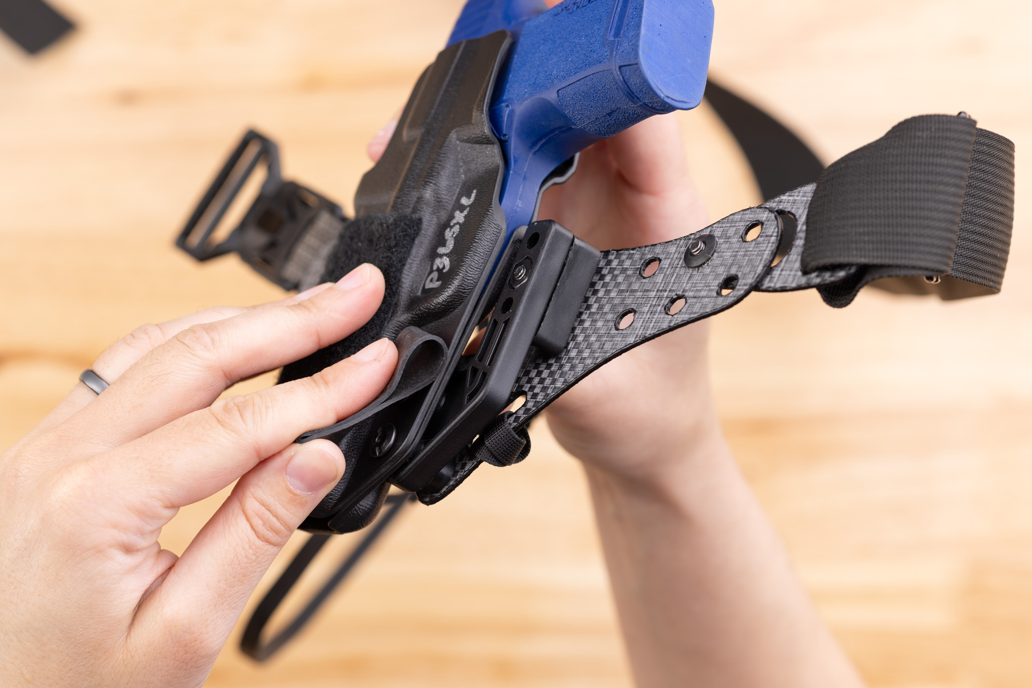 Photo of using a rubber band to tighten the screws holding the holster to the Enigma faceplate.